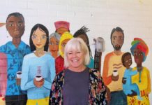 Kitti Murray, fundadora de Refuge Coffee Co., una empresa sin fines de lucro que ofrece empleo y capacitación a los refugiados, posa el 18 de septiembre junto a un mural pintado en la sede de la organización en Clarkston, una pequeña localidad al este de Atlanta, Georgia. EFE