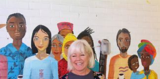 Kitti Murray, fundadora de Refuge Coffee Co., una empresa sin fines de lucro que ofrece empleo y capacitación a los refugiados, posa el 18 de septiembre junto a un mural pintado en la sede de la organización en Clarkston, una pequeña localidad al este de Atlanta, Georgia. EFE