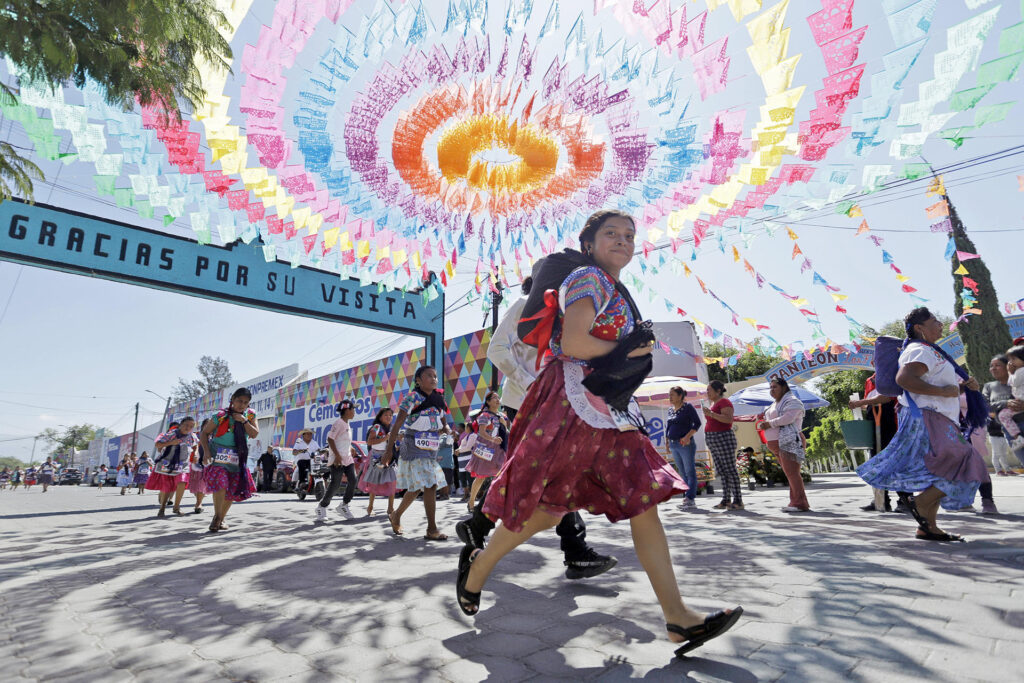 Mujeres de distintas edades participan con sus trajes tradicionales en la 'Carrera de la Tortilla' este domingo, en Santa Maria Coapan, en el estado de Puebla (México). EFE