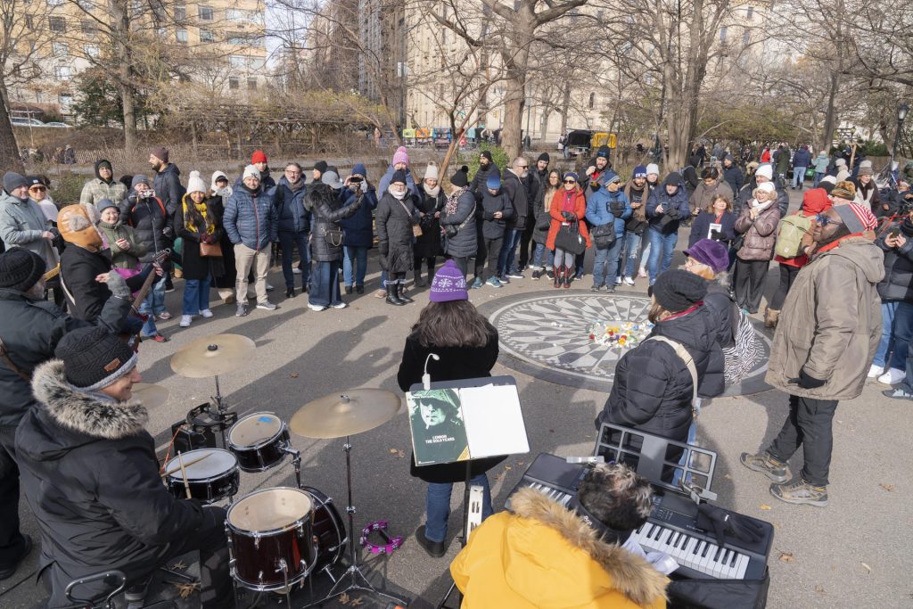 Personas participan en la conmemoración de los 45 años de muerte de John Lennon alrededor de un mosaico este lunes, en Nueva York. EFE
